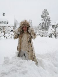 Portrait of smiling young woman standing in snow