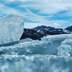 Scenic view of ice with mountains in background against sky