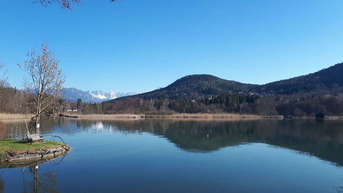 Scenic view of lake and mountains against clear blue sky