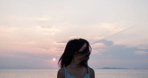 Young woman against sea during sunset
