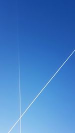 Low angle view of vapor trail against clear blue sky