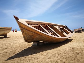 Boat moored on beach against sky