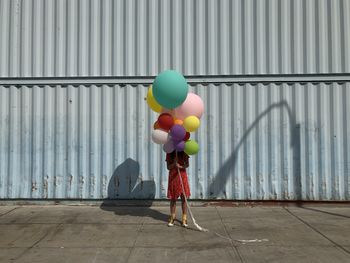 Rear view of woman with balloons on footpath