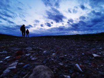 People walking on land against sky during sunset