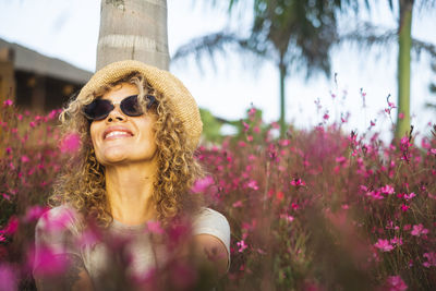 Portrait of young woman wearing sunglasses against trees