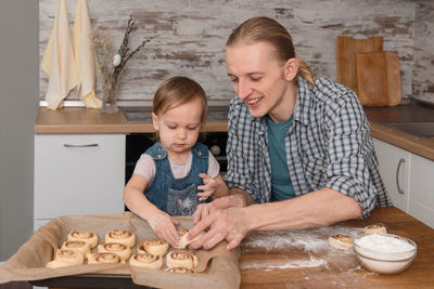 Father and child cooking on the kitchen with fun. family baking cinnabon