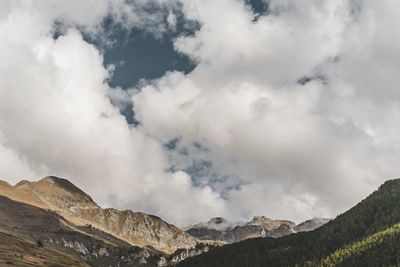 Low angle view of clouds over mountains against sky