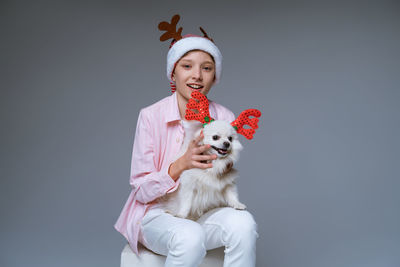 Cheerful boy in hat with deer antlers holds dog in his arms, which is also