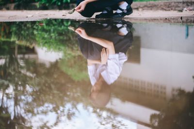 Low section of woman holding reflection in lake