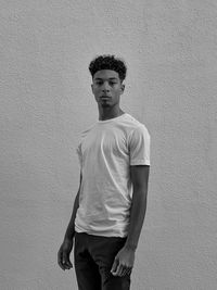 Portrait of young man standing against wall