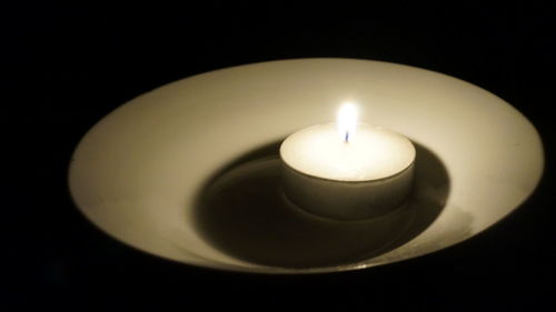 Close-up of lit candle over black background