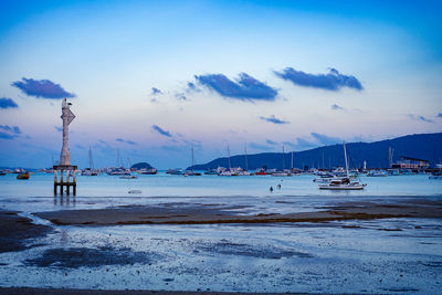 Sailboats moored on sea against sky at sunset