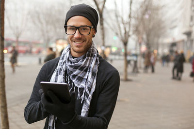 Portrait of smiling young man standing on mobile phone in city