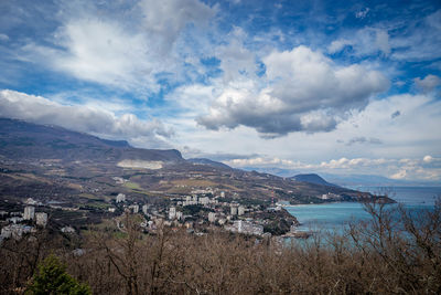 Aerial view of townscape by sea against sky