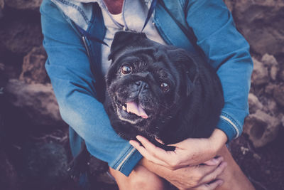 Midsection of woman holding black dog