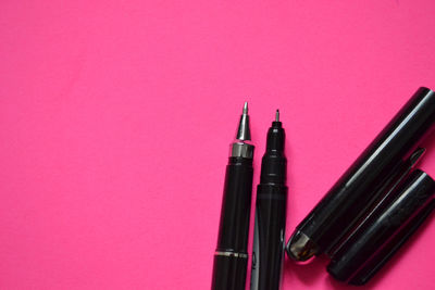 High angle view of pink pen against colored background
