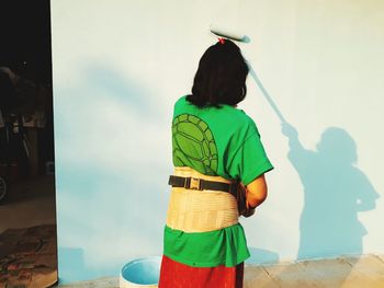 Rear view of woman painting wall