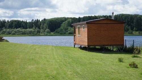 House by lake against sky