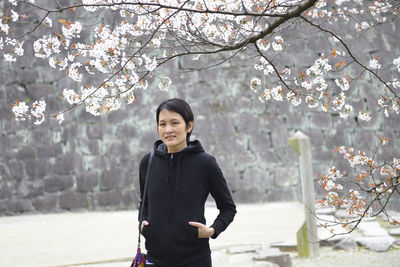 Young woman standing by tree