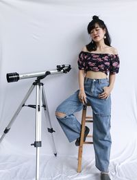 Portrait of young woman looking away while standing against wall