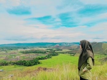 Woman standing by plants against sky