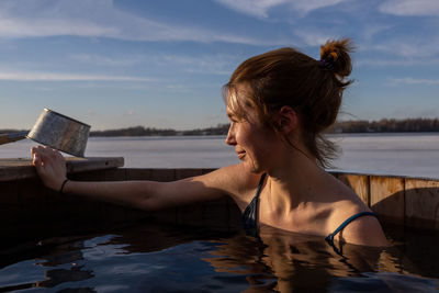 Rear view of young woman using mobile phone in sea