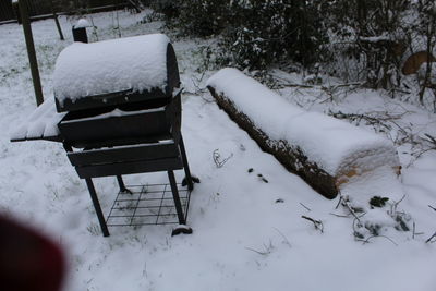 Empty bench on snow covered field during winter