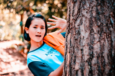 Portrait of boy smiling on tree trunk