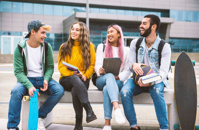 Cheerful friends holding book outdoors