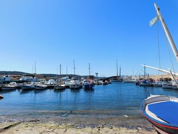 Sailboats moored at harbor against clear blue sky