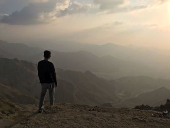 Rear view of man standing on mountain during sunset