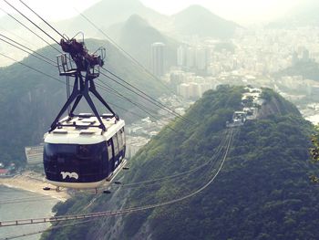 Overhead cable car against city by mountains