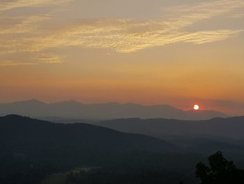 Scenic view of silhouette mountains against orange sky