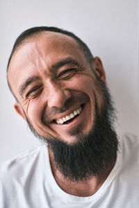 Happy muslim man with beard dressed in white t-shirt is laughing. human emotions. looking at camera