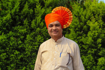 Portrait of senior man in turban standing against trees