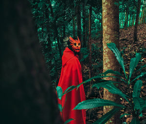 Woman wearing mask while standing amidst trees in forest