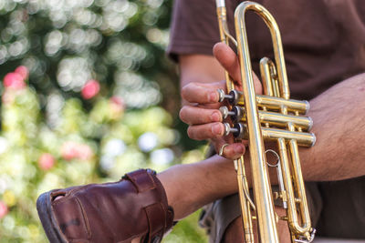 Low section of man holding trumpet sitting outdoors