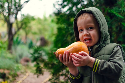 Little boy holds a pumpkin in his arm. harvesting and preparing for halloween. 