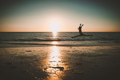 Silhouette people at beach against sky during sunset