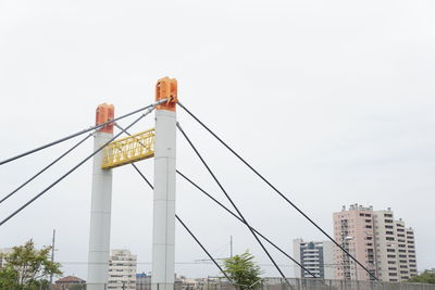 Low angle view of bridge by buildings against sky