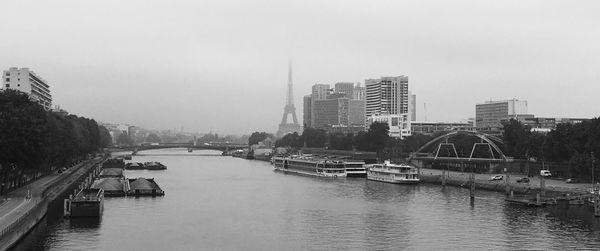 View of eiffel tower by seine river against foggy sky in paris 