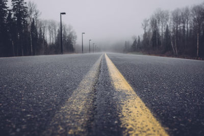 Close-up of road with foggy trees in background