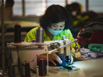 Woman using sewing machine while working in factory