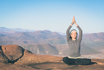 Portrait of young woman in desert against clear sky