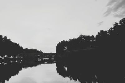 Reflection of silhouette trees on river against sky