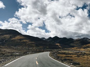 Road leading towards mountains against sky