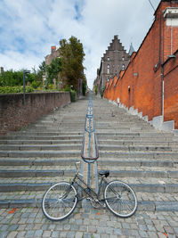 Bicycle parked by building against sky