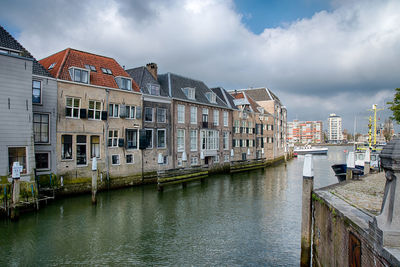 Buildings by river against sky in city