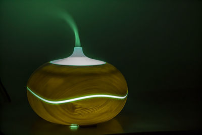 Close-up of illuminated electric lamp with smoke on table