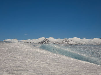 Scenic view of snowcapped mountains against clear blue sky